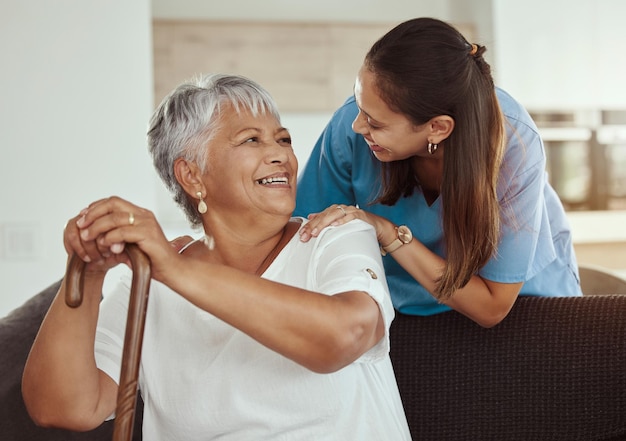 Foto feliz relax e mulher sênior com sorriso de cuidador enquanto está sentado em um sofá da sala de estar em um lar de idosos ajuda de suporte e enfermeira profissional ou profissional de saúde ajudando senhora idosa ou paciente