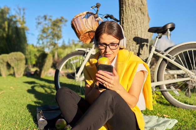 Feliz relaxante mulher madura em fones de ouvido com um smartphone