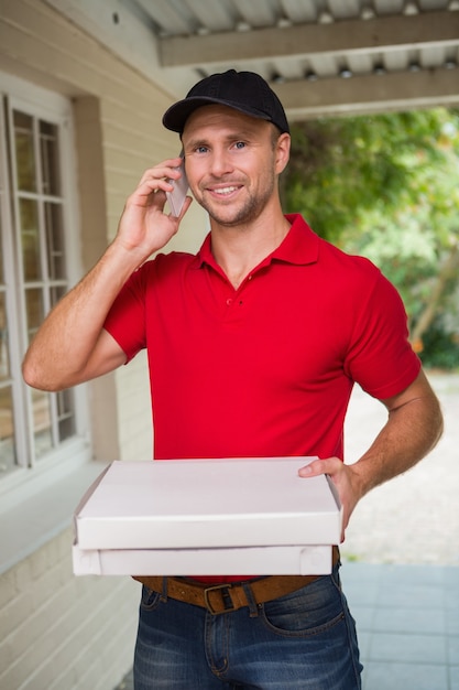 Feliz repartidor de pizza en el teléfono