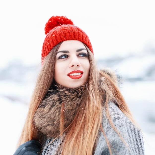 Feliz retrato de una bella mujer bonita con labios rojos y una sonrisa en invierno día nevado