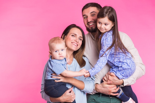 Feliz retrato de familia de raza mixta sonriendo en la pared rosa