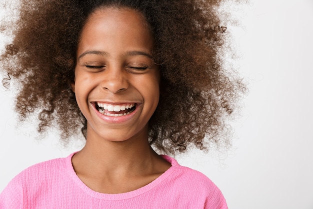 Feliz rindo criança jovem africana posando isolado sobre uma parede branca.