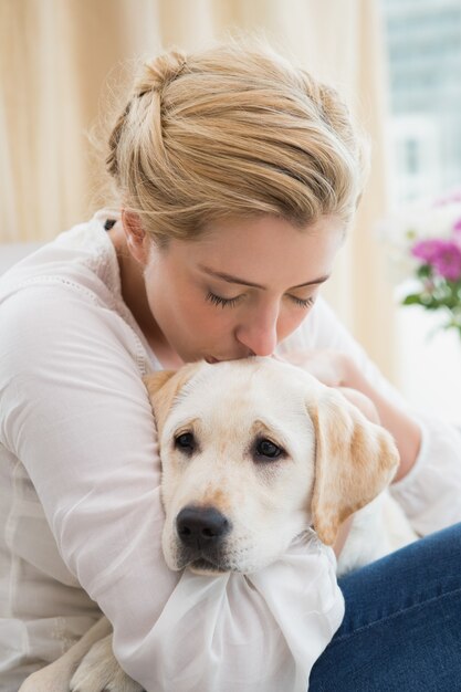 Feliz rubia abrazos con cachorro en el sofá