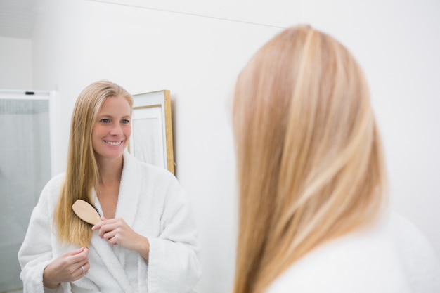 Feliz rubia cepillando su cabello