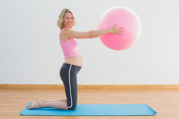 Foto feliz rubia embarazada levantando la bola del ejercicio