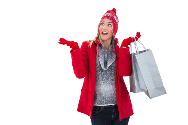 Feliz rubia en ropa de invierno con bolsas de compras