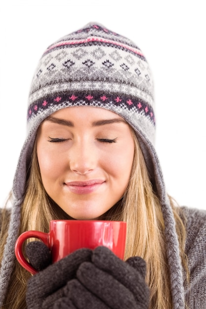 Feliz rubia en ropa de invierno sosteniendo la taza