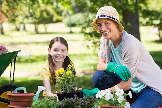 Feliz rubia y su hija jardinería en un día soleado