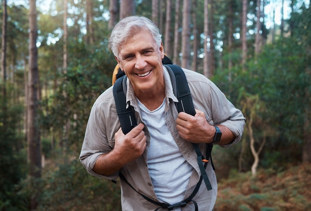 Feliz senderismo y retrato de un anciano en la naturaleza para relajarse, hacer senderismo y aventura Viajar bienestar y vacaciones con un hombre mayor caminando en el bosque para la jubilación, mochilero y resistencia cardiovascular