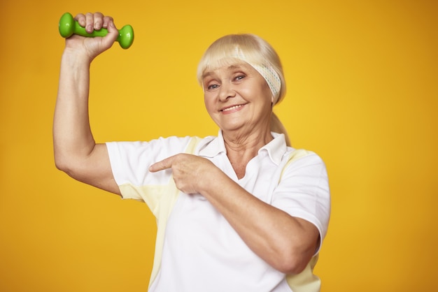 Foto feliz senhora idosa fazendo exercício de halteres bíceps