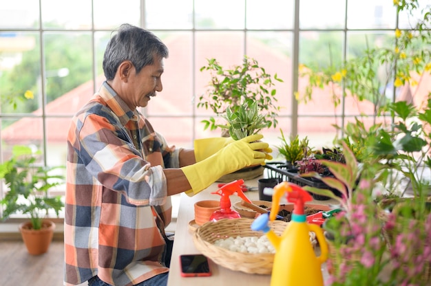 Un feliz senior asiático jubilado rociar y regar el árbol disfruta de la actividad de ocio en casa