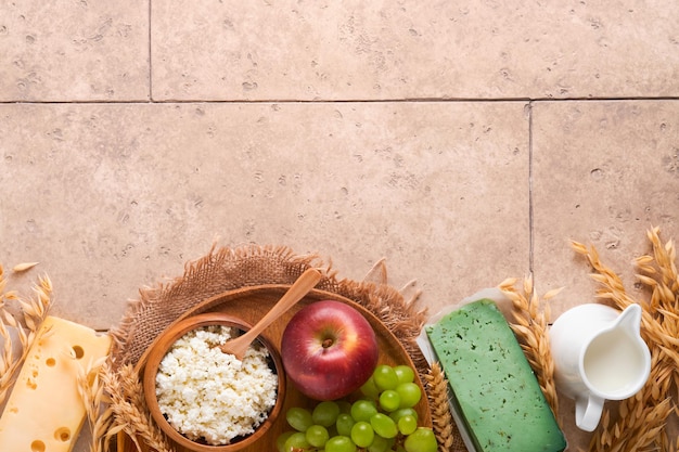 Feliz Shavuot Fondo para la celebración de Shavuot Leche y queso trigo maduro y frutas fondo de madera azul Productos lácteos sobre la vieja pared de azulejos agrietados Concepto de Shavuot Vista superior Mock up