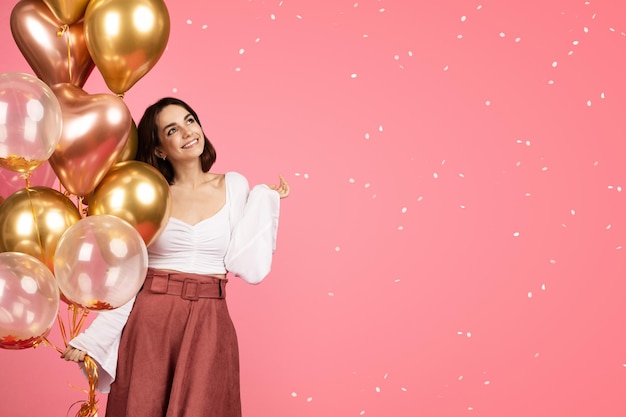 Feliz soñadora joven caucásica con muchos globos inflables disfruta de confeti