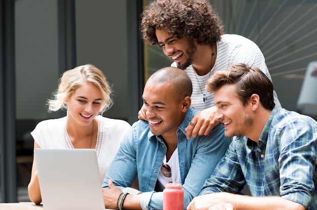 Feliz sonriendo chicos y chicas estudiando con el portátil en el café