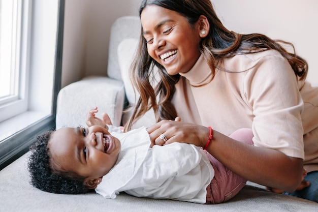 Feliz sonriendo riendo madre india jugando con negra niña hija familia gente de raza mixta