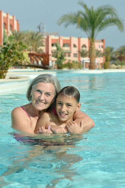 Feliz sonriente abuela y nieto en el agua de la piscina azul