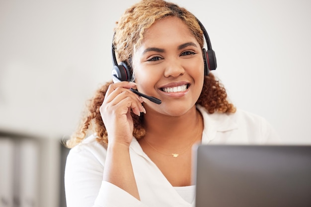 Feliz, sonriente y amigable agente del centro de llamadas que usa auriculares mientras trabaja en una oficina