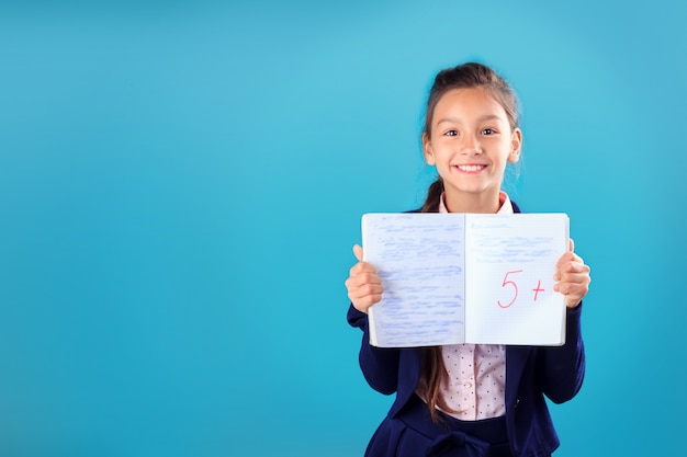 Feliz sonriente colegiala en uniforme sosteniendo y mostrando portátil con excelentes resultados de prueba o examen