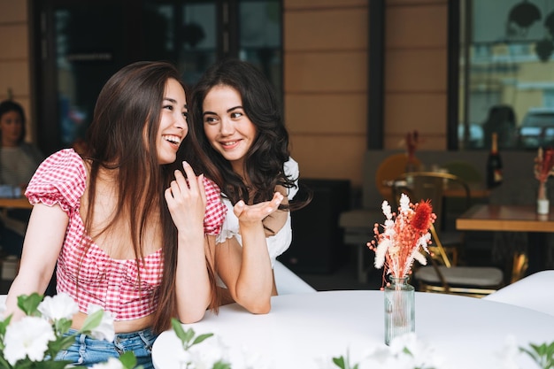 Foto feliz sonriente hermosa morena mujeres jóvenes con hablar en la terraza de café de verano chicas despreocupadas