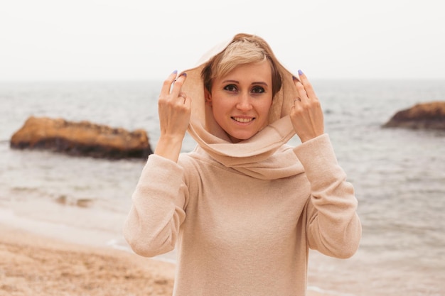 Feliz sonriente hipster joven caminando en la playa de arena cerca del primer plano del mar