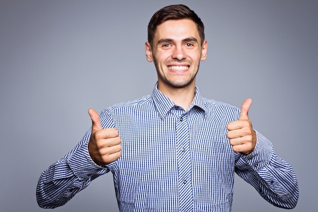Feliz sonriente hombre de negocios con pulgares arriba gesto sobre fondo gris