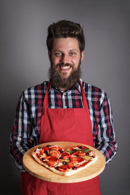 Foto feliz sonriente hombre sujetando pizza casera en forma de corazón