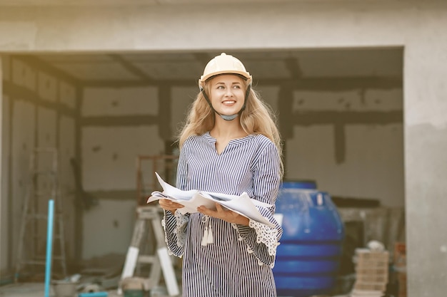 Feliz sonriente ingeniera en un casco imagina cuán hermosa será la vivienda que construirá, retrato