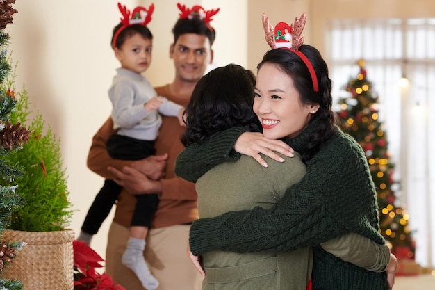 Feliz sonriente joven abrazando a su madre mayor que vino para la celebración navideña