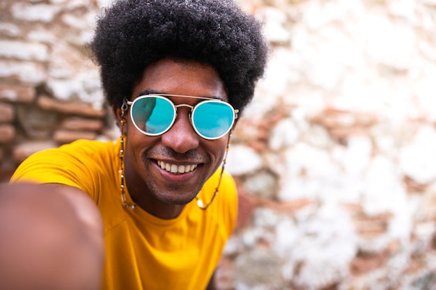 Feliz sonriente joven afroamericano tomando selfie Espacio de copia Fondo de pared de ladrillo Concepto de estilo de vida