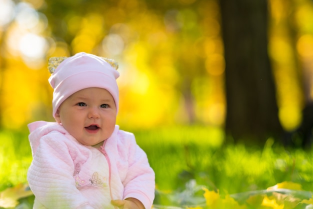 Feliz sonriente joven amigable niña sentada en la hierba en otoño bosque en un retrato de cerca con espacio de copia