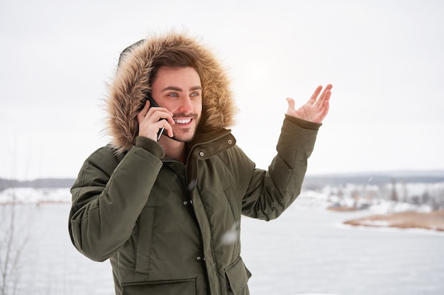 Feliz sonriente joven caucásico hablando por teléfono Invierno