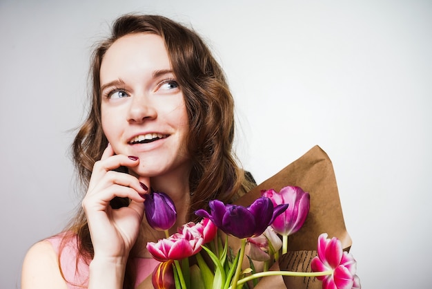 Feliz sonriente joven celebrando el día mundial de la mujer el 8 de marzo, en manos de un ramo de flores.