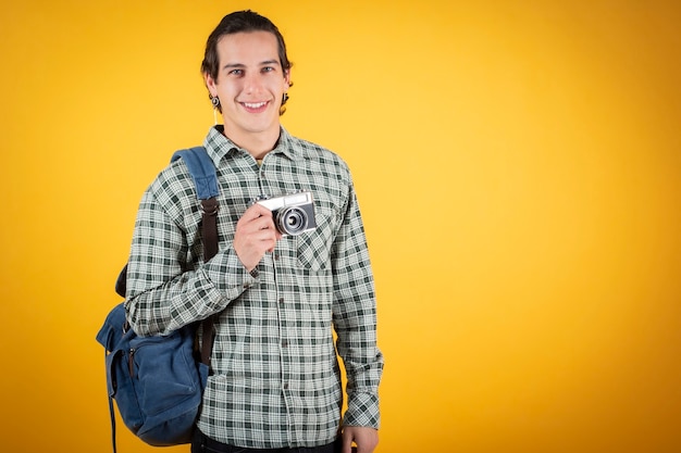 Feliz sonriente joven guapo, caucásico, con una cámara y una mochila, nómada digital, viajero.