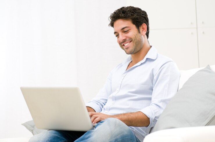 Foto feliz sonriente joven mirando y trabajando en la computadora portátil en casa
