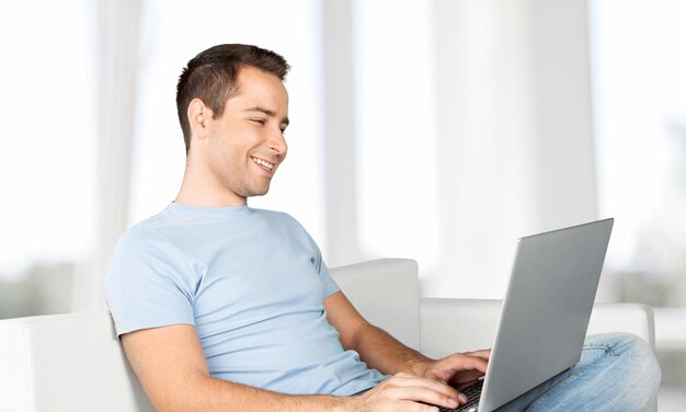 Feliz sonriente joven mirando y trabajando en la computadora portátil en casa