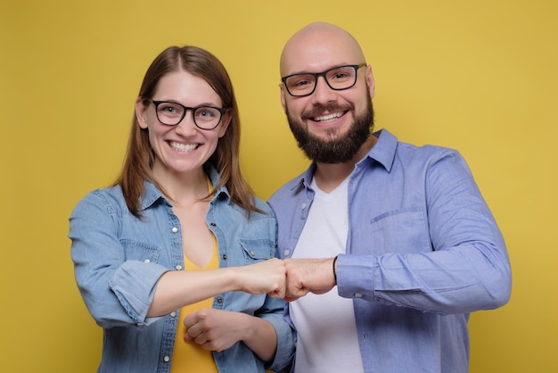 Foto feliz sonriente joven pareja de amigos hombre y mujer dan golpes de puño mirando a la cámara