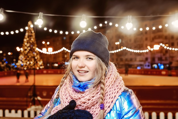 Feliz sonriente mujer caucásica en guantes de chaqueta bufanda sombrero por la pista al aire libre