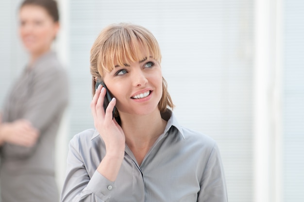 Feliz sonriente mujer de negocios hablando por móvil en la oficina