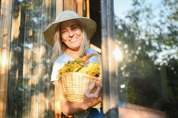 Feliz sonriente mujer senior posando con flores