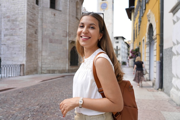 Feliz sonriente mujer turista visitando la antigua ciudad medieval de Trento, Italia