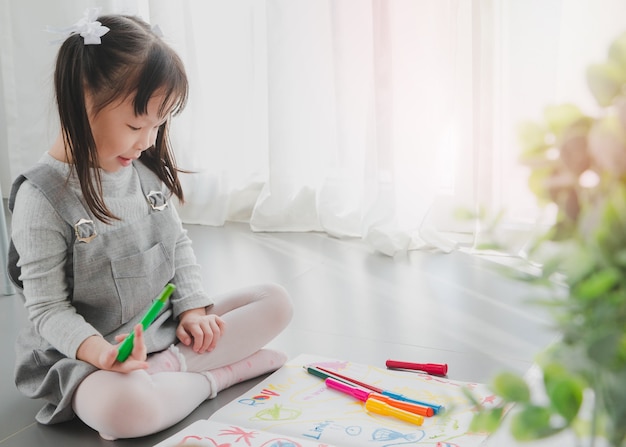 Feliz sonriente niña asiática dibujo y pintura de color en el cuaderno