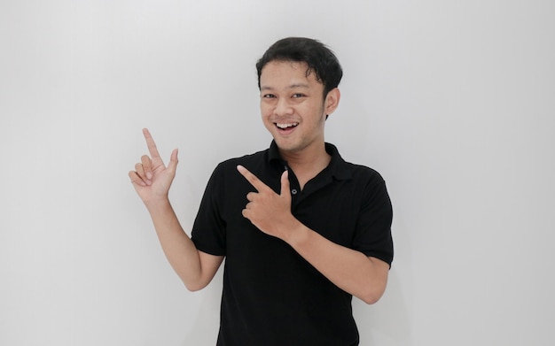 Feliz y sonrisa de joven asiático con punto de mano en el espacio vacío Indonesia Hombre usa camisa negra Fondo gris aislado