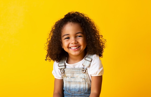 Feliz sorridente criança africana-americana menina fundo amarelo