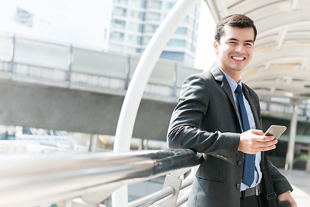 Feliz sorridente empresário latino-americano, usando telefone celular ao ar livre na cidade