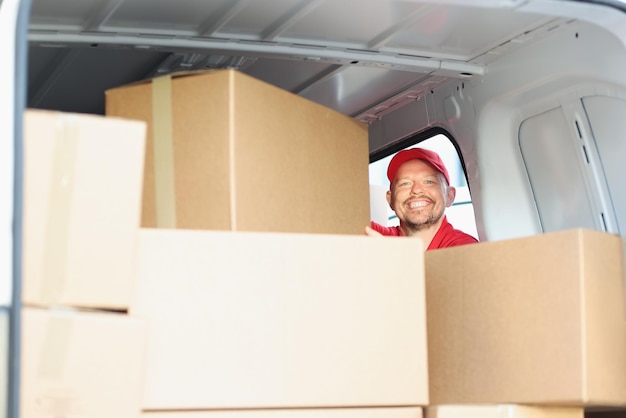 Feliz sorridente homem de meia idade no trabalho colocou caixas de papelão no caminhão para entrega