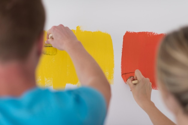 feliz sorridente jovem casal pintando a parede interior da casa nova