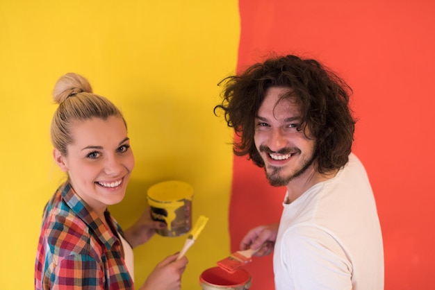 feliz sorridente jovem casal pintando a parede interior da casa nova