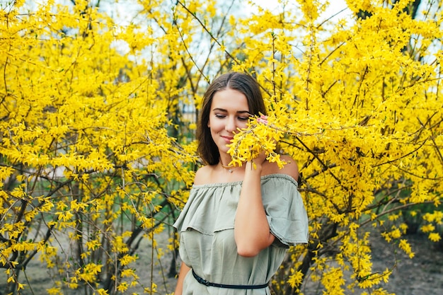 Feliz sorridente jovem com flores da primavera no jardim