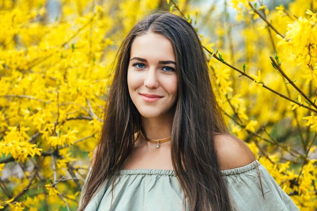 Feliz sorridente jovem com flores da primavera no jardim