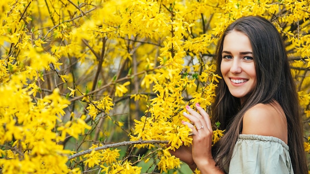 Feliz sorridente jovem com flores da primavera no jardim